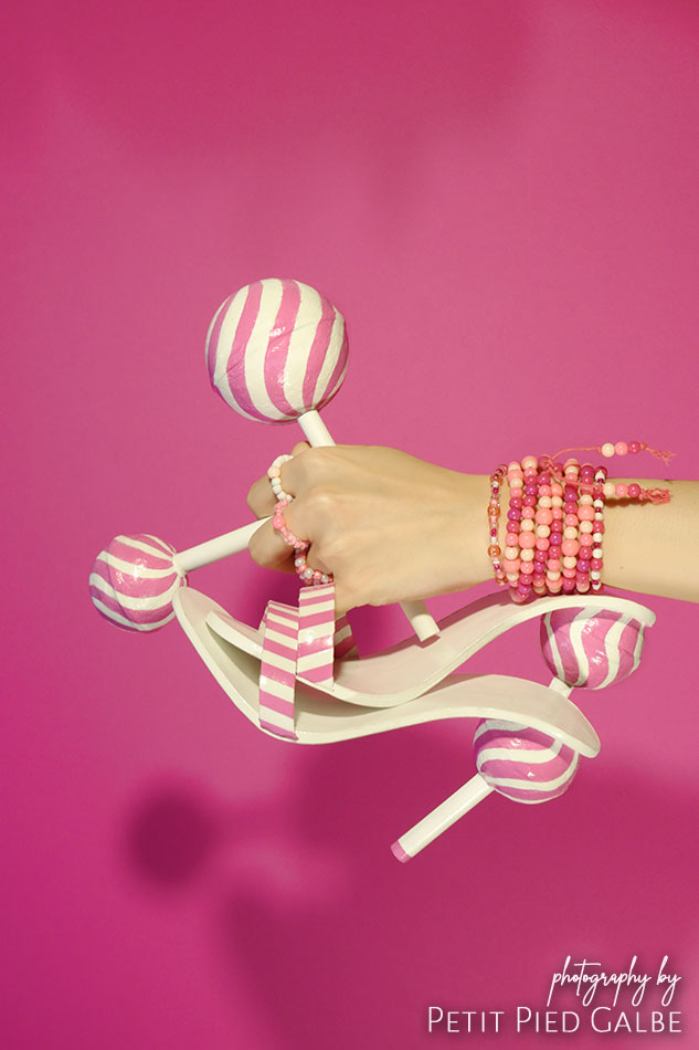 Model holding in hand conceptual shoes and sweets. Concept of pink fashion.