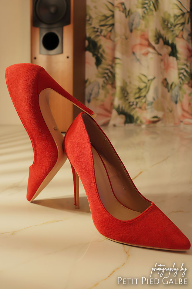 Red high heels standing on the floor in elegant interior in day light.