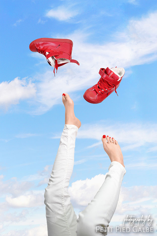 Captured in motion, picture of a girl who kicks off her shoes against the blue sky.